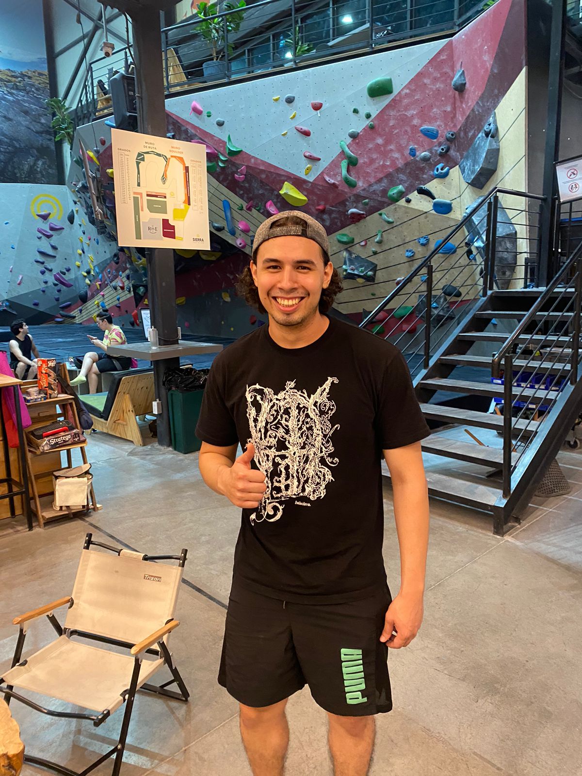 Emilio in a bouldering gym, smiling, with a thumbs up